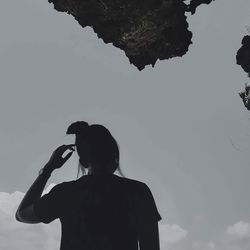 Rear view of silhouette man photographing woman against sky