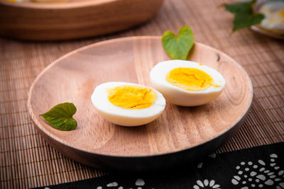 Close-up of boiled egg in wooden plate on table