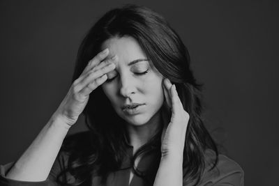 Portrait of young woman against black background