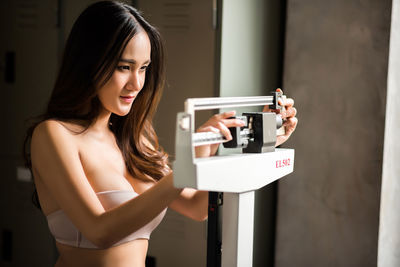 Young woman standing on weight scale in gym