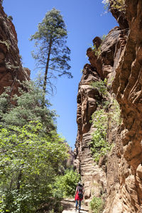 Low angle view of people on rock against sky