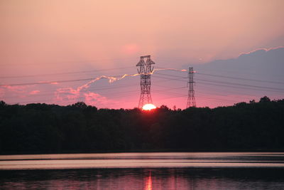 Scenic view of lake by trees against cloudy sky during sunset