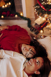Smiling female friends relaxing at home during christmas