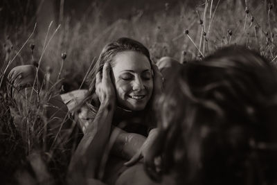 Black and white gentle girlfriend lying on boyfriend in field in summer and enjoying weekend