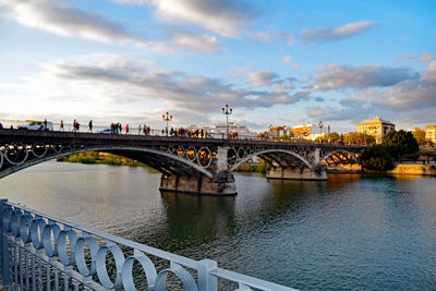 Bridge over river in city against sky