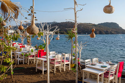 Chairs and tables on beach by sea against clear sky