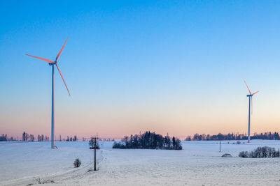 Wind turbines on field against sky during sunset