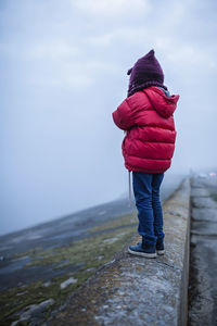 Rear view of child on snow against sky