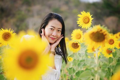 Portrait of young woman standing amidst sunflowers