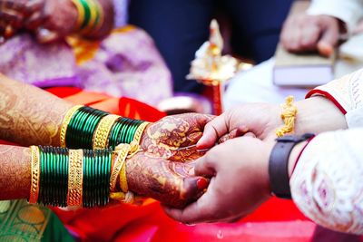 Cropped image of wedding couple holding hands during ceremony