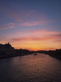 Scenic view of river against cloudy sky during sunset