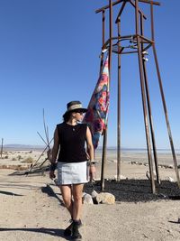 Full length of young woman standing on land against clear sky