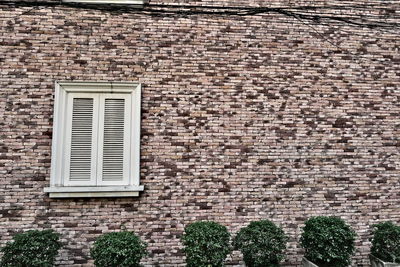 Low angle view of window on brick wall of building