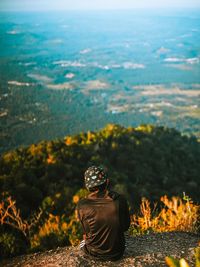 Rear view of woman sitting on landscape against sky