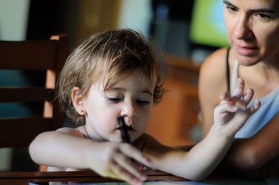 Shirtless girl with mother using digital tablet at home