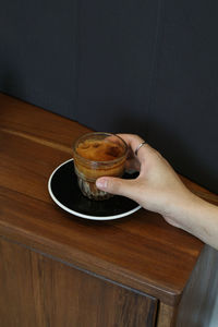 Cropped hand of woman holding coffee on table