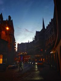 City street amidst buildings against sky at dusk