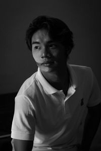 Portrait of young man standing against black background