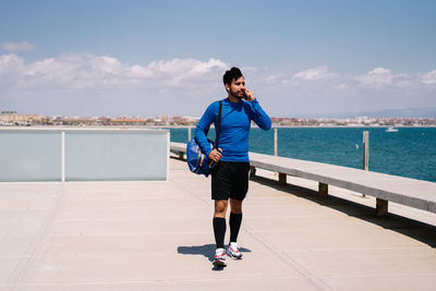 Full length of man standing on railing against sea