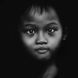 Close-up portrait of young woman over black background