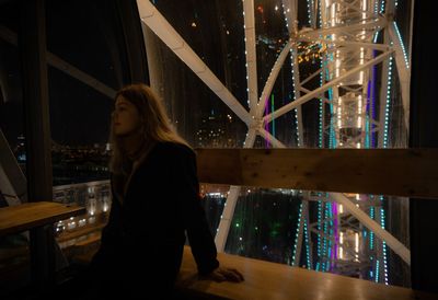 Woman sitting in carousel at night