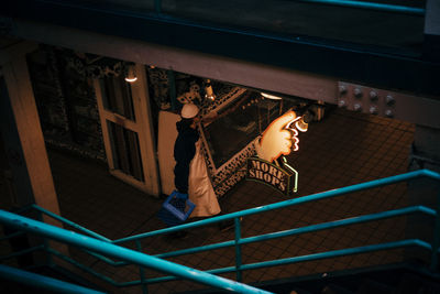 Low angle view of woman looking at illuminated staircase