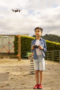 Child flying remote control drone in park very concentrated