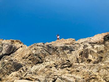 Low angle view of rocks against clear blue sky