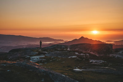 Silhouette woman standing on mountain against sky during sunset