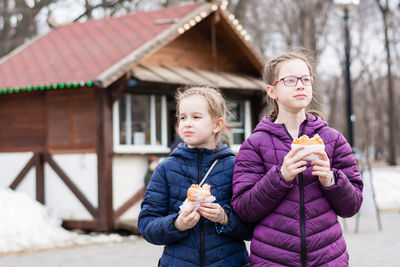 Two girls sisters eat pies bought in a food truck in a city park. takeaway food
