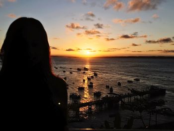 Silhouette woman relaxing on beach against sky during sunset