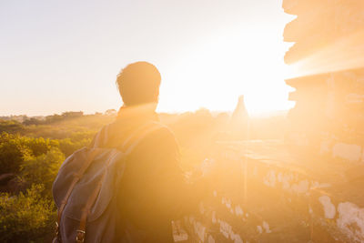 Rear view of man standing against sky during sunset