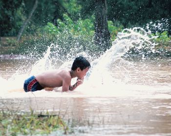 Full length of shirtless boy splashing water