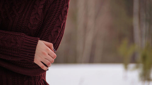 Midsection of woman wearing sweater while standing at park during winter