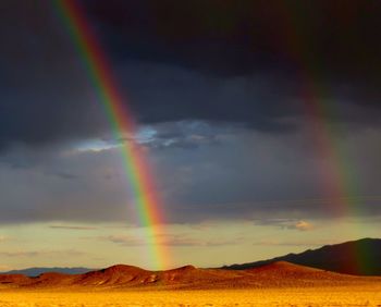 Scenic view of rainbow over mountain against sky
