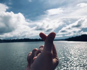 Cropped hand snapping finger against sea