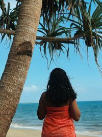 Rear view of woman looking at sea shore against sky