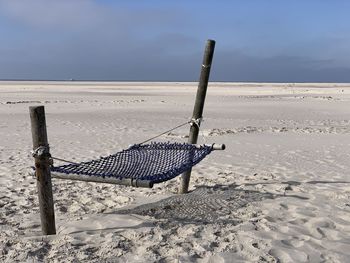 Wooden posts on beach against sky during winter