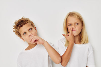 Cute sibling picking nose against white background