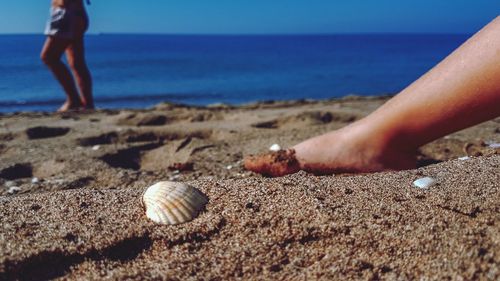 Midsection of person at beach against sky