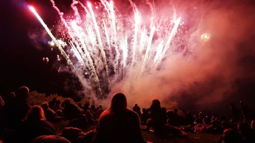 Rear view of people looking at firework display