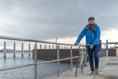 Low angle view of man standing on railing against sky