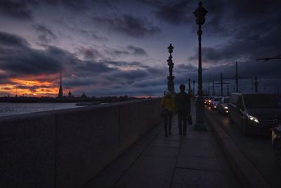 People walking on pathway along calm sea