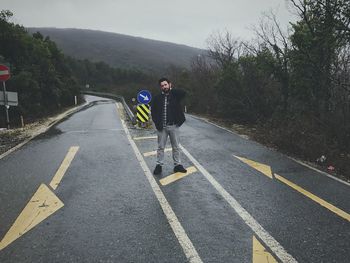 Portrait of man standing on road against mountain
