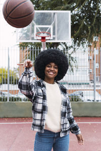 Young woman throwing basketball standing on sports court