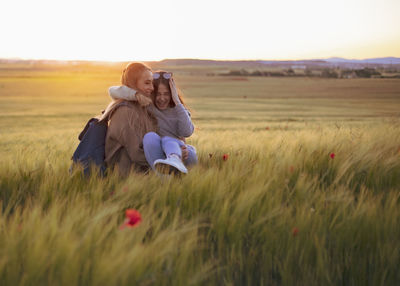 Two women holding hands at sunset in the field