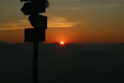 Silhouette mountains against orange sky during sunset
