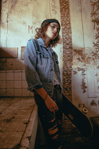 Portrait of young woman standing on wall