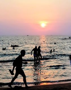 Silhouette people on beach against sky during sunset