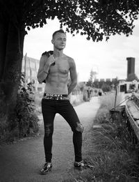 Full length portrait of young man standing against trees